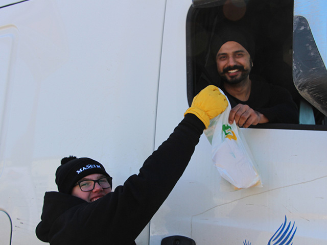 man giving another man a sandwich.